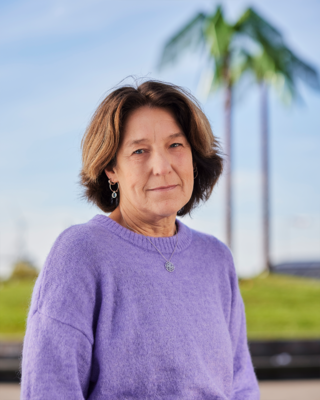 Frau in blauem Pullover steht vor blauem Himmel mit einer Palme aus Stahl, dem Park Fiction in Hamburg.
