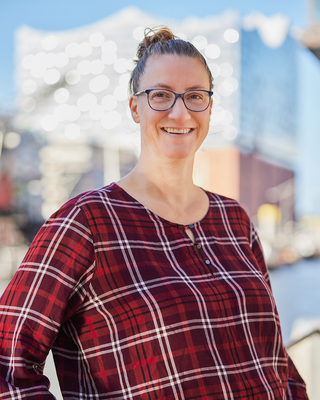 Eine Frau steht vor der Elbphilharmonie und lacht