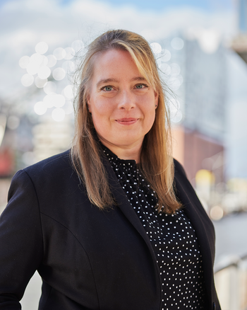 Eine Frau steht vor der Elbphilharmonie und lächelt.