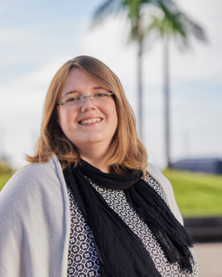 Eine Frau sitzt vor künstlichen Palmen und lacht.