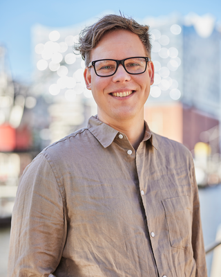 Ein Mann steht vor der Elbphilharmonie und lacht